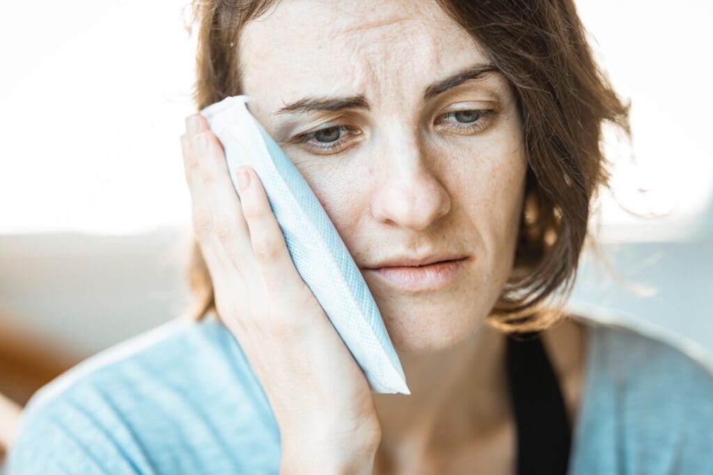 woman putting icebag on face after wisdom tooth removal