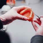 dentist examining a dental crown on a model tooth after root canal treatment.