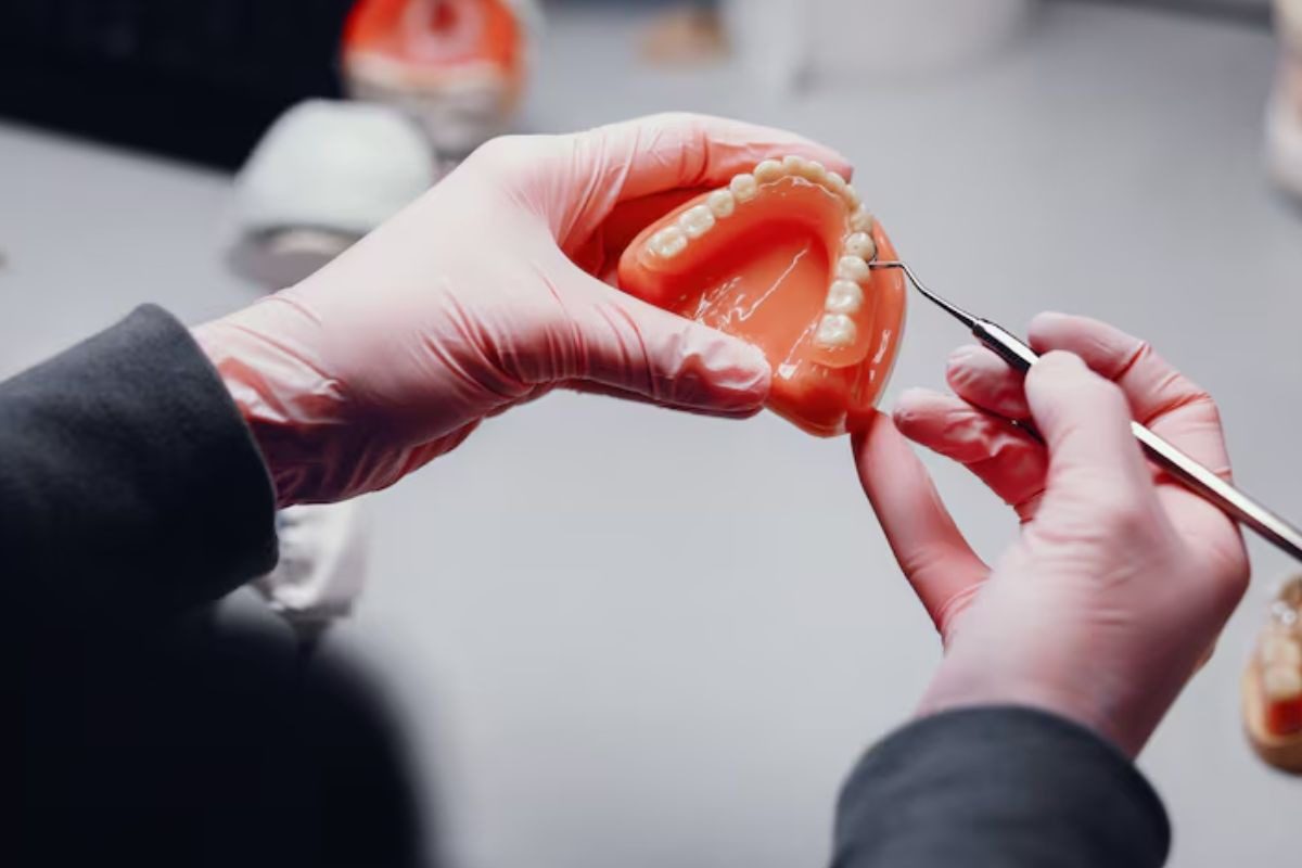 dentist examining a dental crown on a model tooth after root canal treatment.